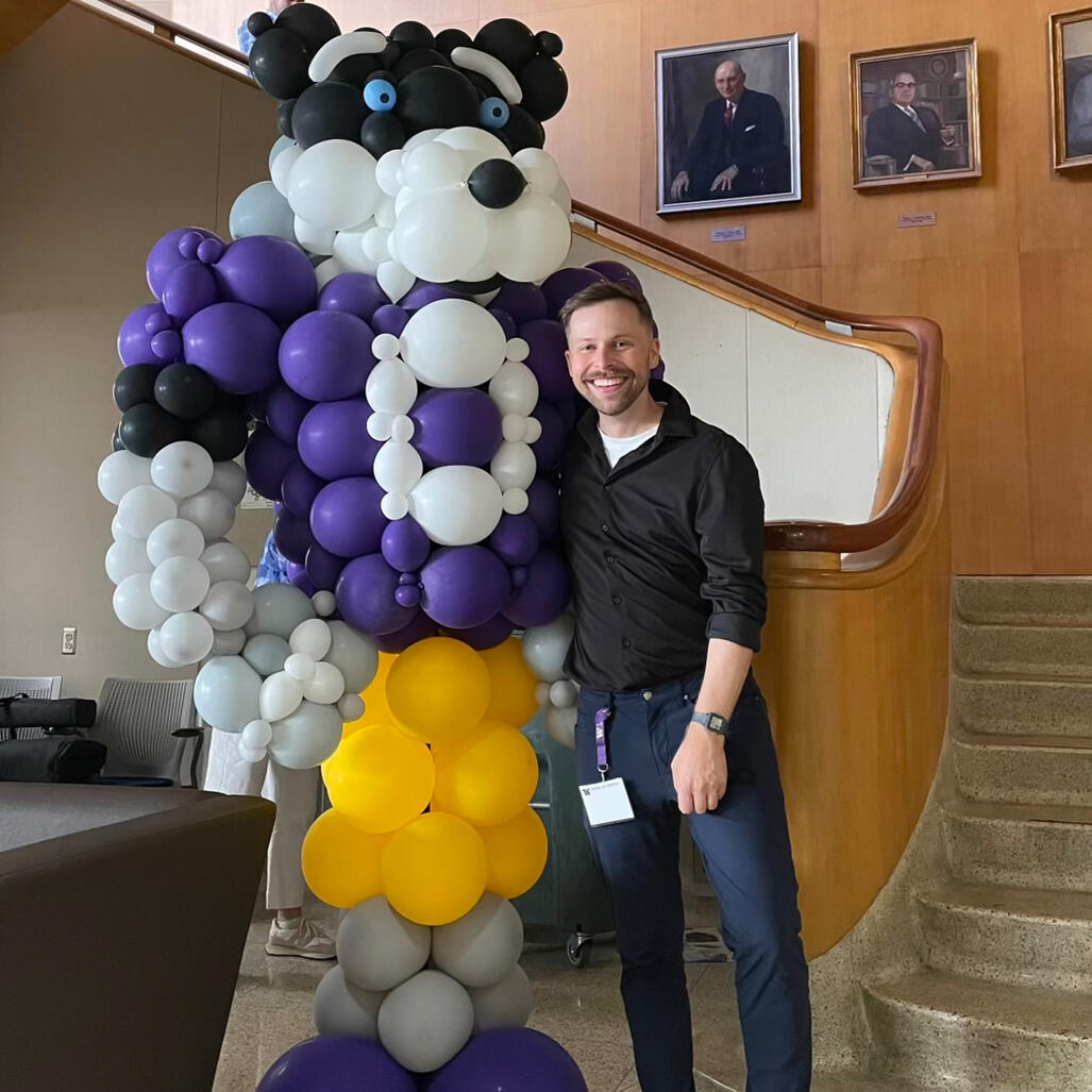 Balloon statue of husky mascot at UW with man standing to the right.